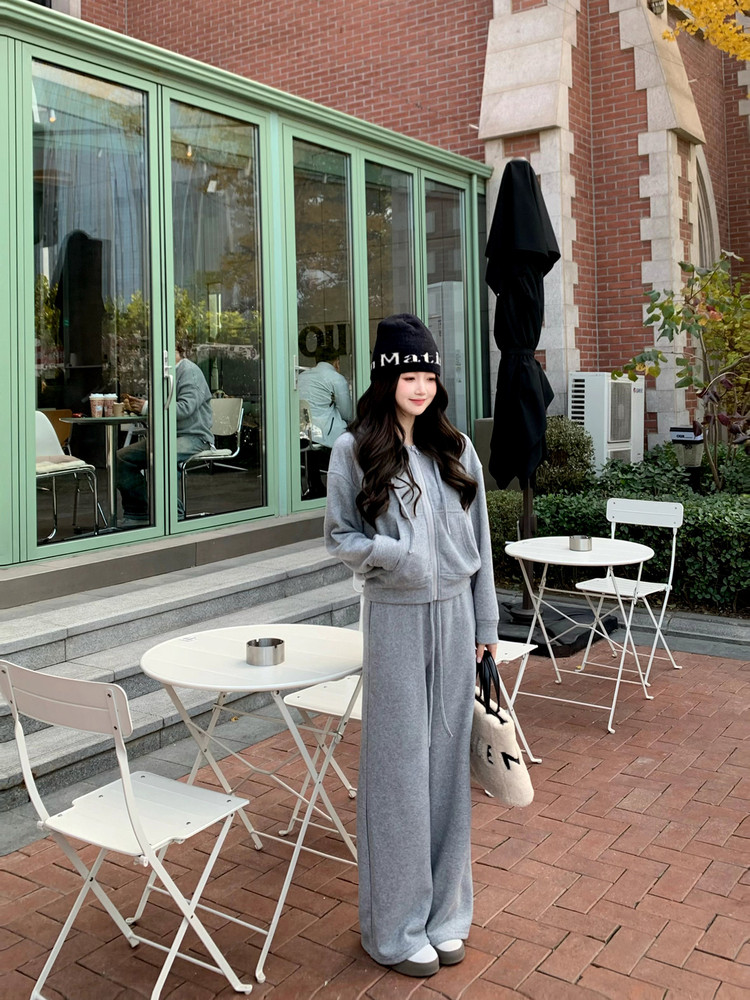 Model wearing a gray loungewear set with a beanie and tote bag outdoors
