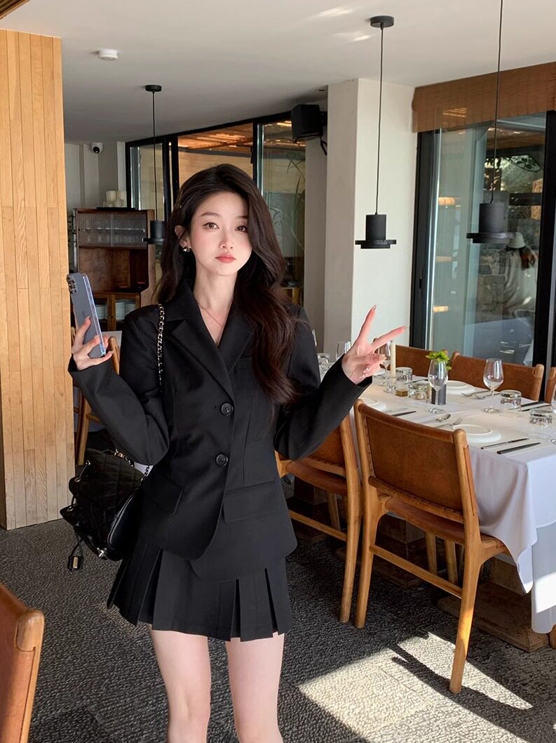 Woman wearing a black blazer and pleated skirt set