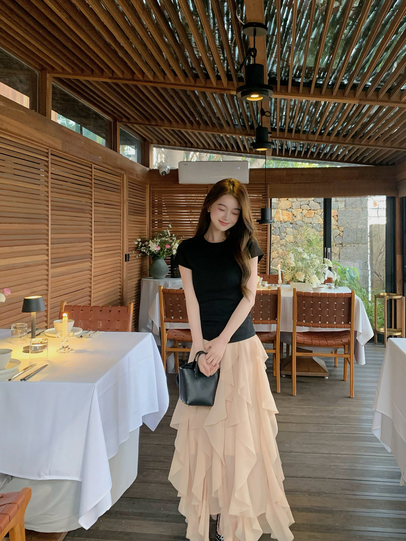 Woman wearing a black top and beige ruffled maxi skirt in a restaurant setting