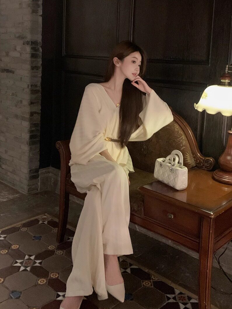 Woman wearing a cream elegant long-sleeve dress with a small white handbag