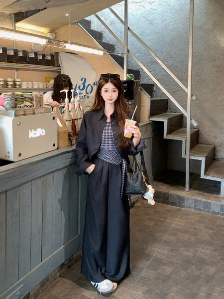 Woman wearing a dark wide-leg outfit with a gingham top in a cafe