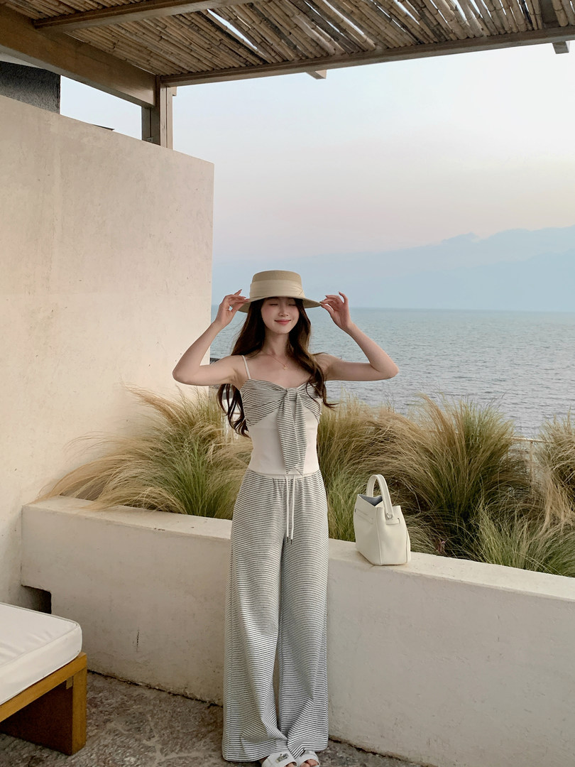 Model wearing a striped sleeveless wide-leg jumpsuit by the sea