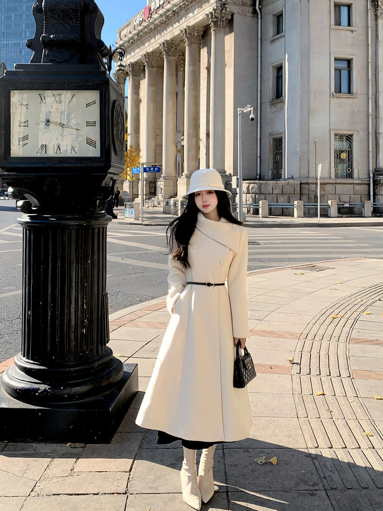 Woman wearing a cream belted coat and matching hat on a city street