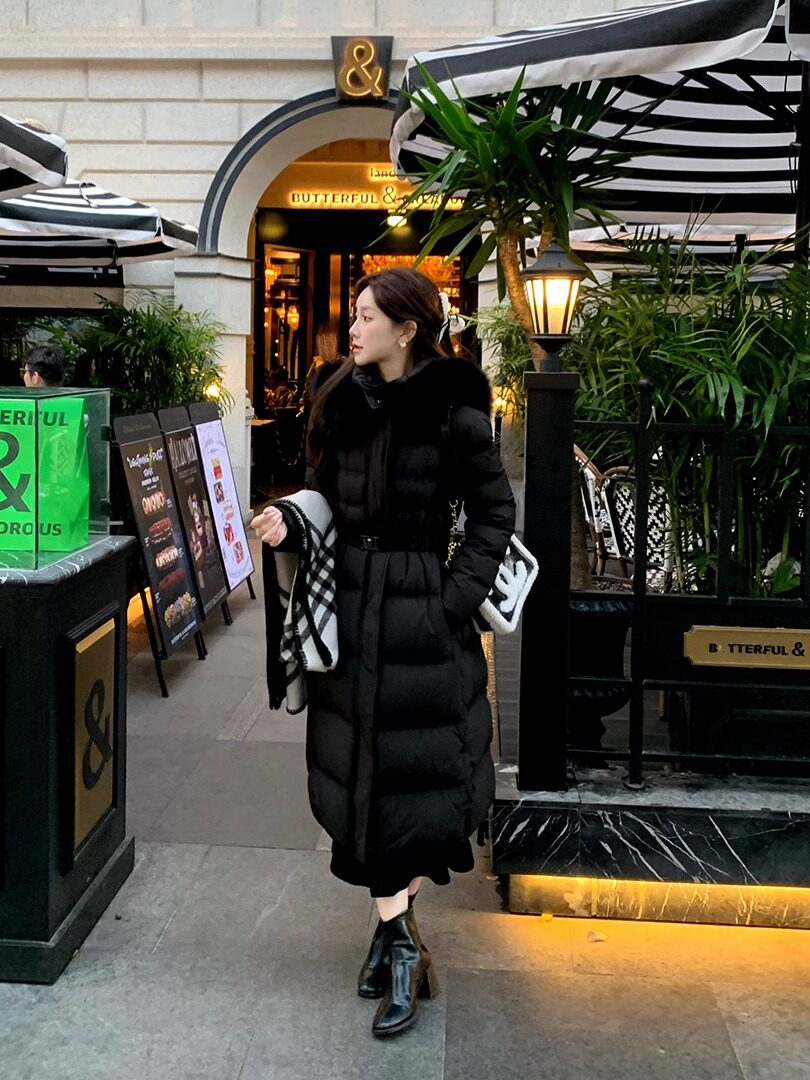 Woman wearing a long black puffer coat with fur collar outdoors