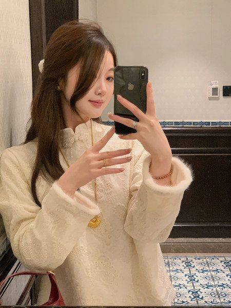 Woman wearing a cream embroidered long-sleeve top with fur-trim cuffs