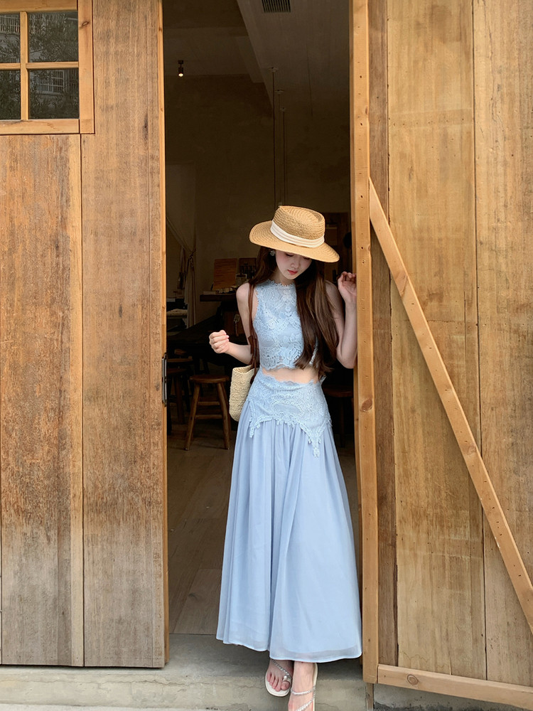 Model wearing a light blue lace crop top and flowy maxi skirt with a straw hat