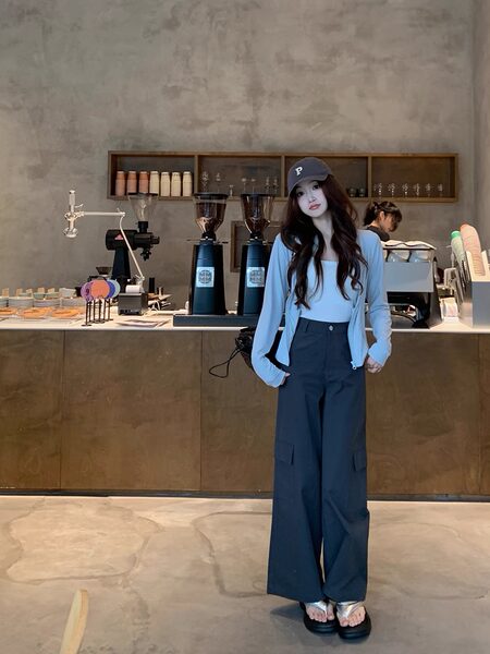 Woman wearing a light blue top and dark wide-leg pants in a cafe
