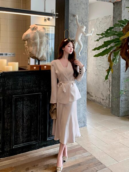 Woman wearing a beige belted blazer and matching midi skirt