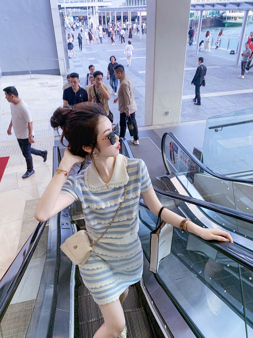 Woman wearing a blue-and-white striped short-sleeve dress on an escalator