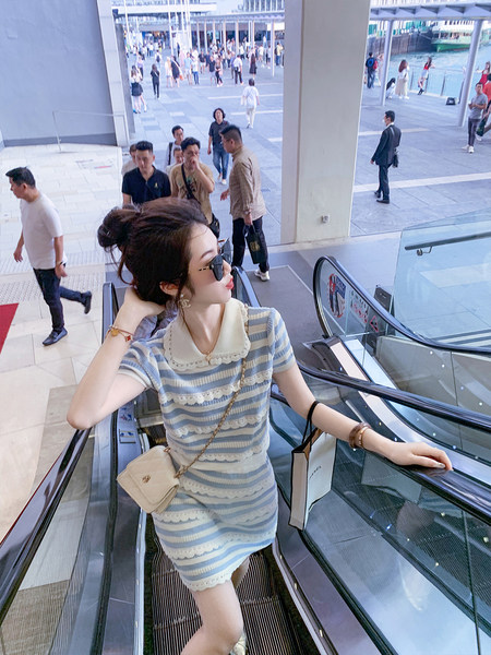 Woman wearing a blue-and-white striped short-sleeve dress on an escalator