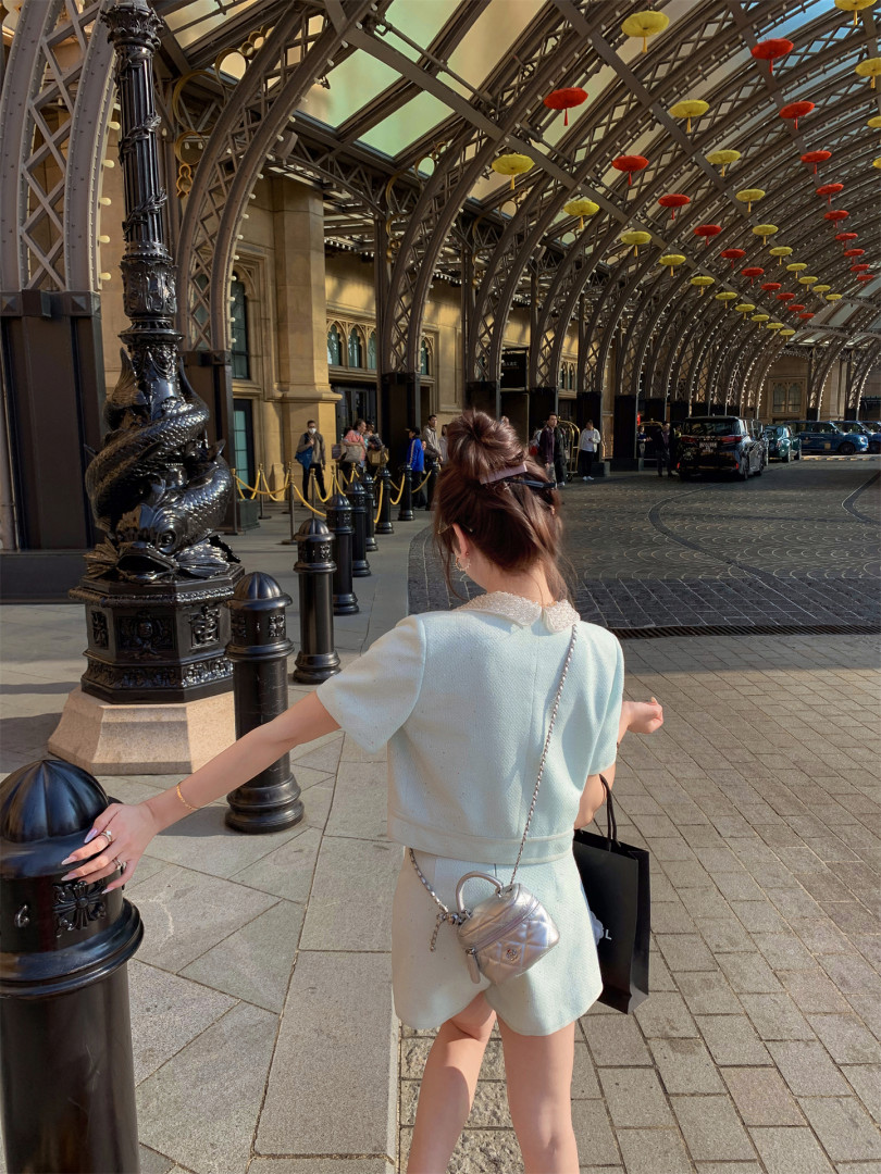 Woman wearing a light blue matching outfit with a small silver crossbody bag outdoors