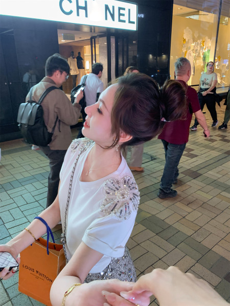 Woman wearing a white embellished top and sequined skirt outside a Chanel store