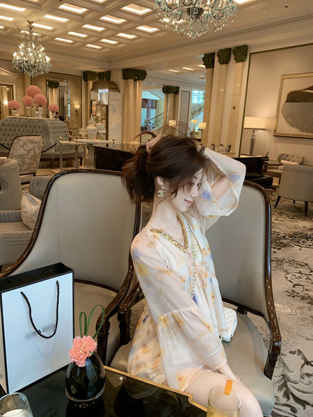 Woman wearing a light floral chiffon dress in a luxury lounge setting