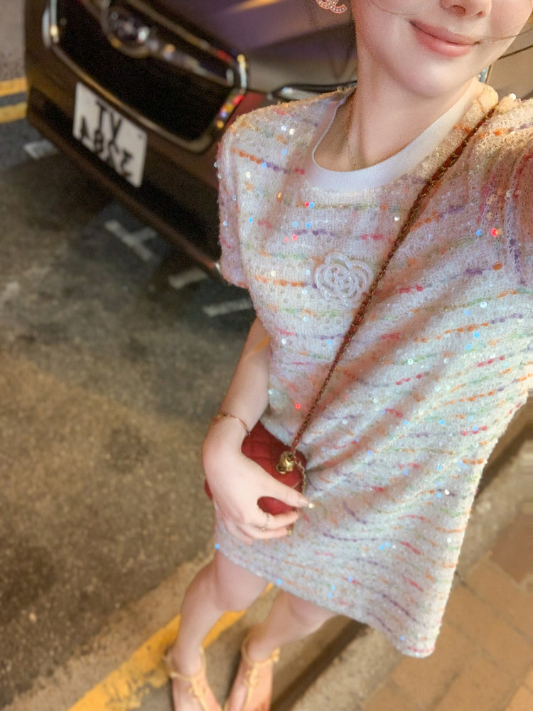 Woman wearing a sparkly short sequined dress with a small crossbody bag