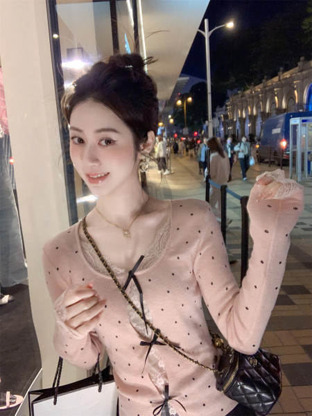 Model wearing a pink polka dot lace-trim top with a black quilted crossbody bag