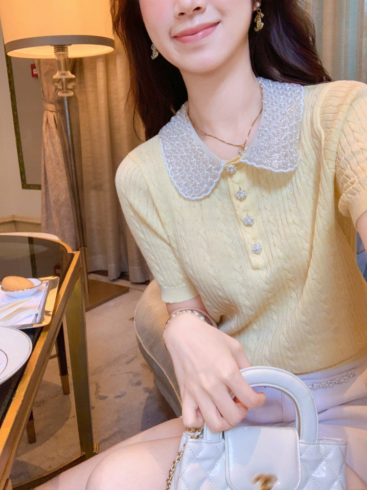 Woman wearing a pale yellow knit top with a lace collar and decorative buttons