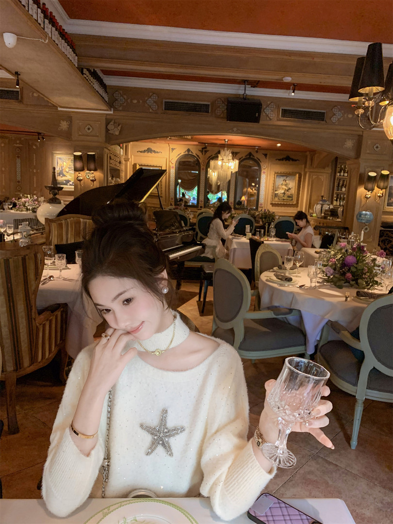 Woman wearing a cream fuzzy embellished sweater at a restaurant table
