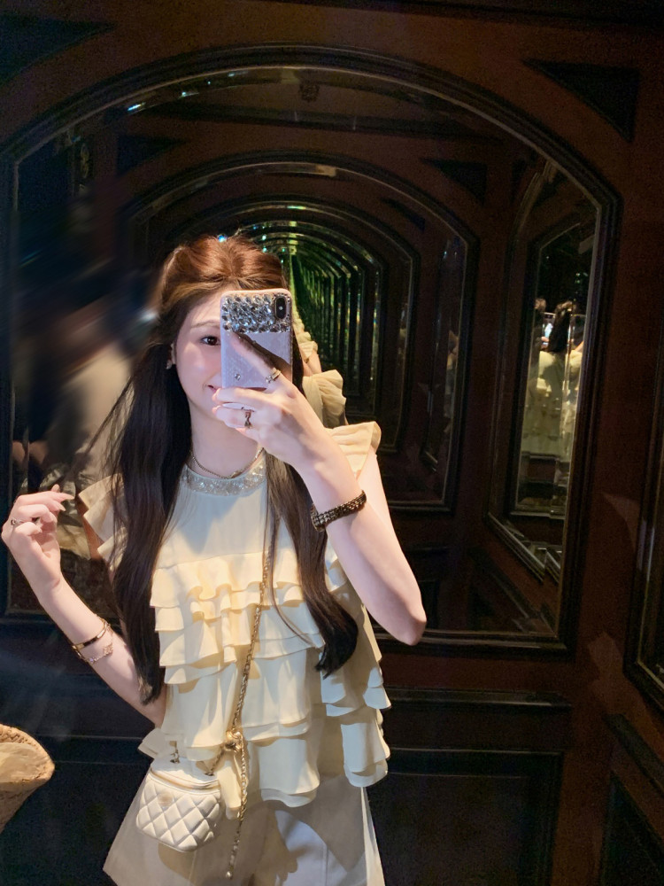 Woman wearing a cream ruffled sleeveless top in a mirror selfie