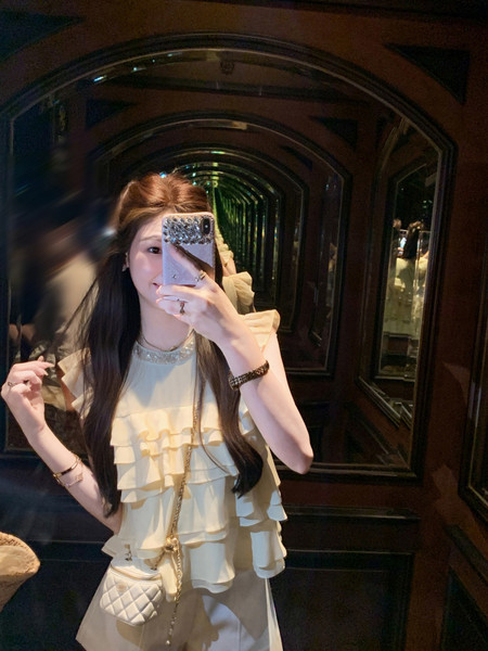 Woman wearing a cream ruffled sleeveless top in a mirror selfie