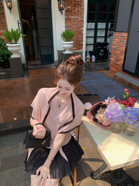 Woman wearing a pink top and black pleated skirt outdoors