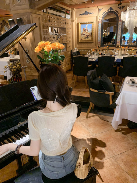 Woman wearing a light beige butterfly-back top in a restaurant setting