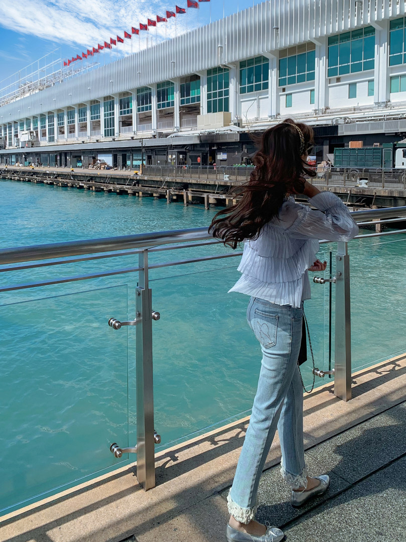 Woman wearing a white blouse and light blue jeans by the waterfront