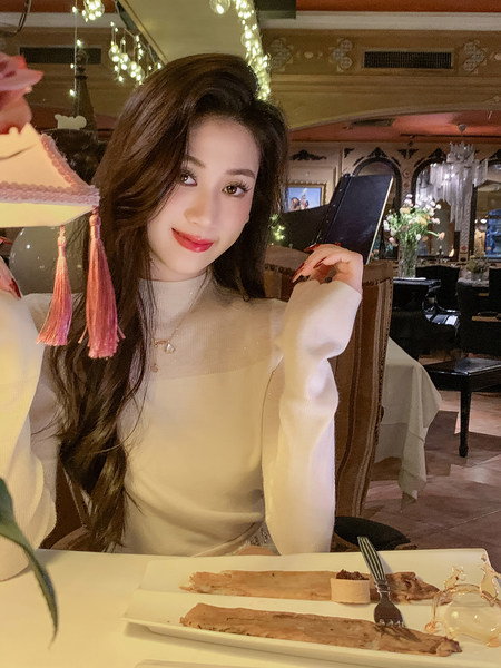 Woman wearing a white long-sleeve top at a restaurant table