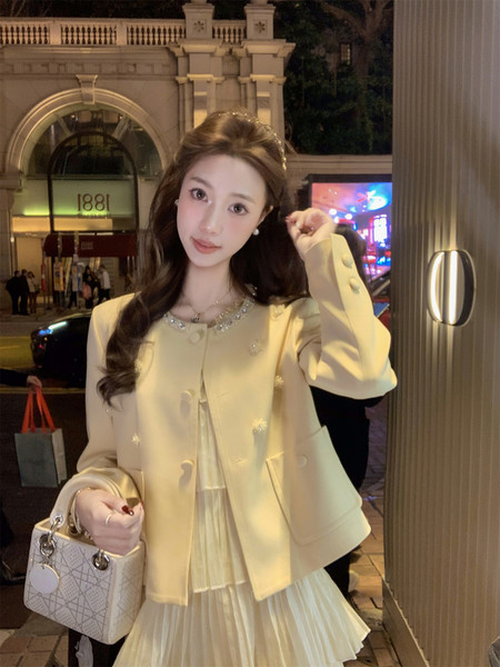 Woman wearing a light yellow elegant outfit with a matching handbag