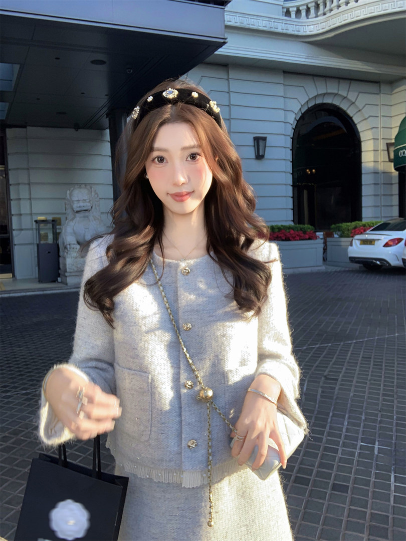 Woman wearing a light gray knit cardigan and matching skirt set with gold buttons