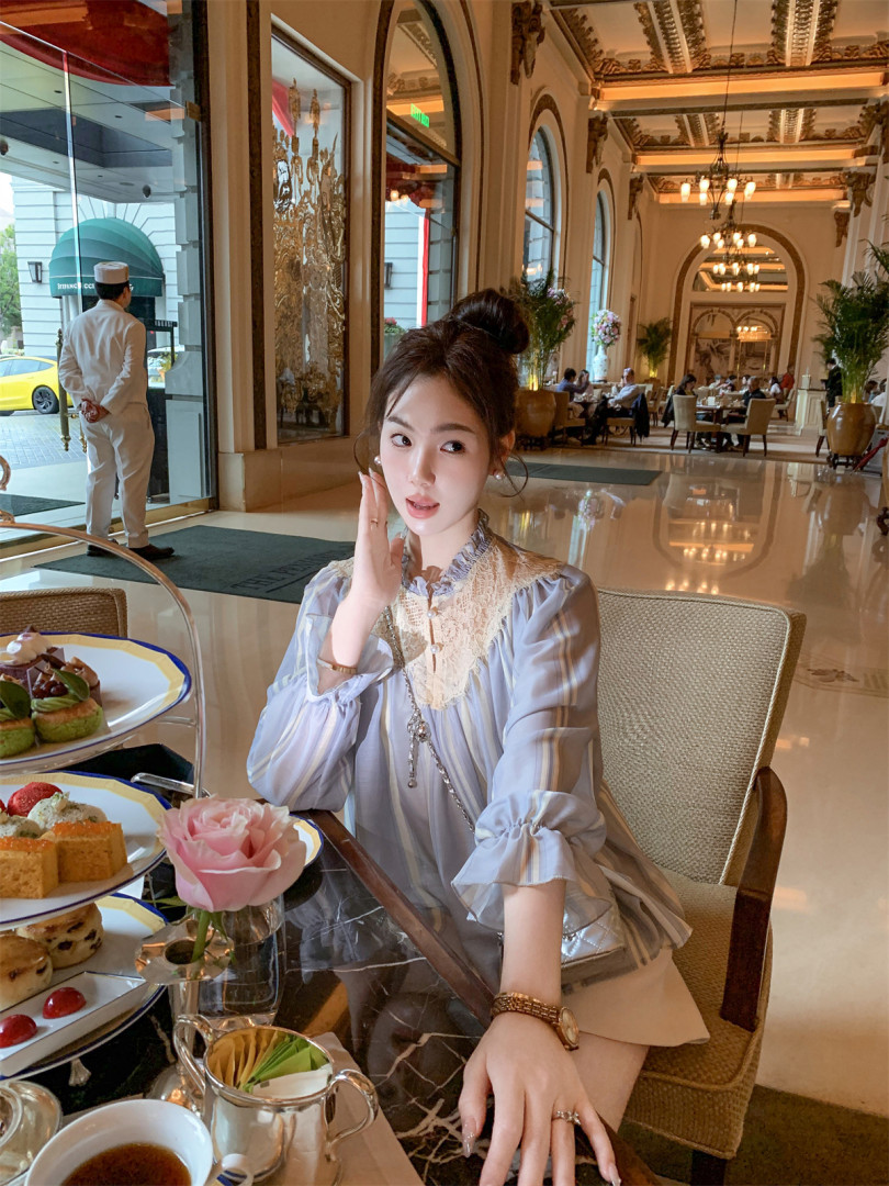 Woman wearing a light blue sheer lace-trim blouse at a restaurant