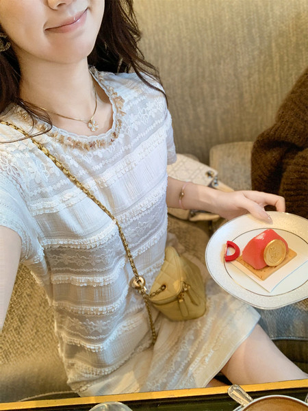 Woman wearing a white lace dress with a small crossbody bag