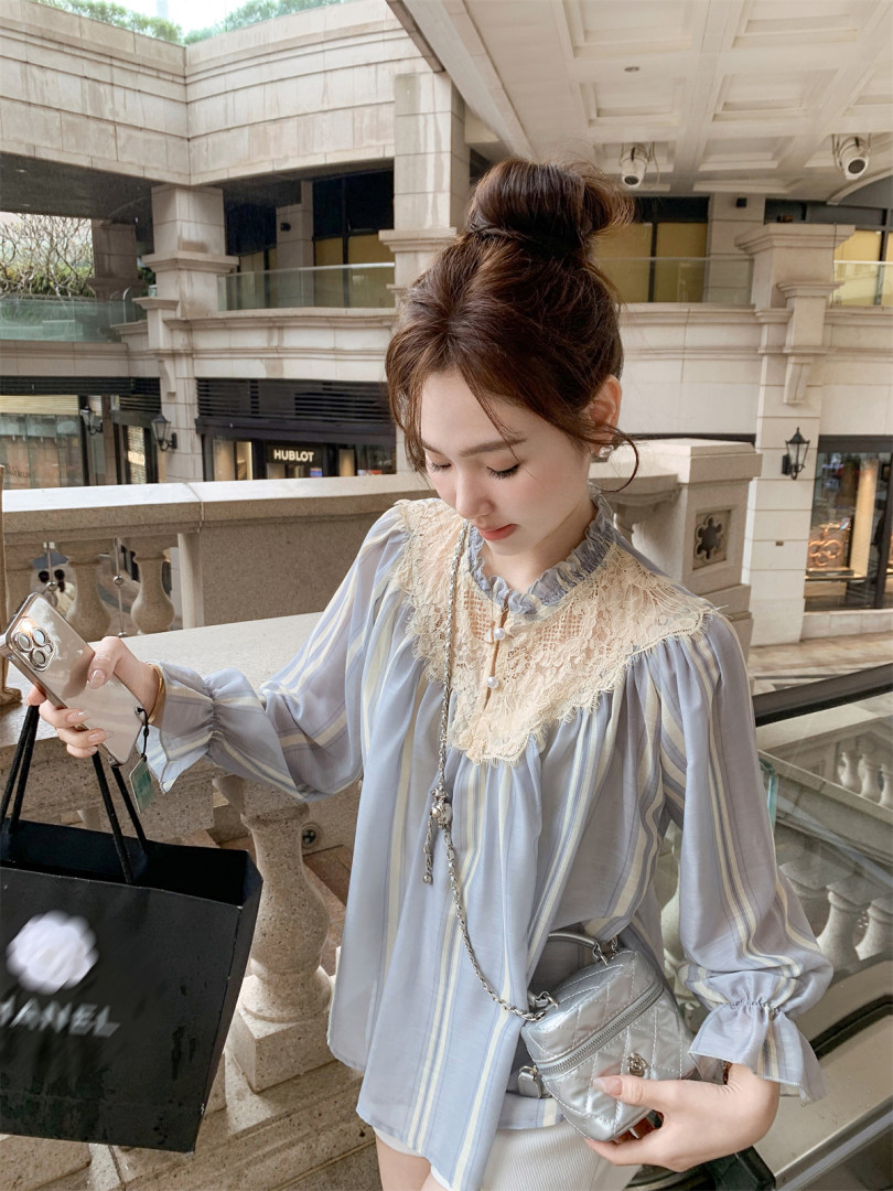 Woman wearing a light blue striped blouse with lace collar and a silver quilted mini bag
