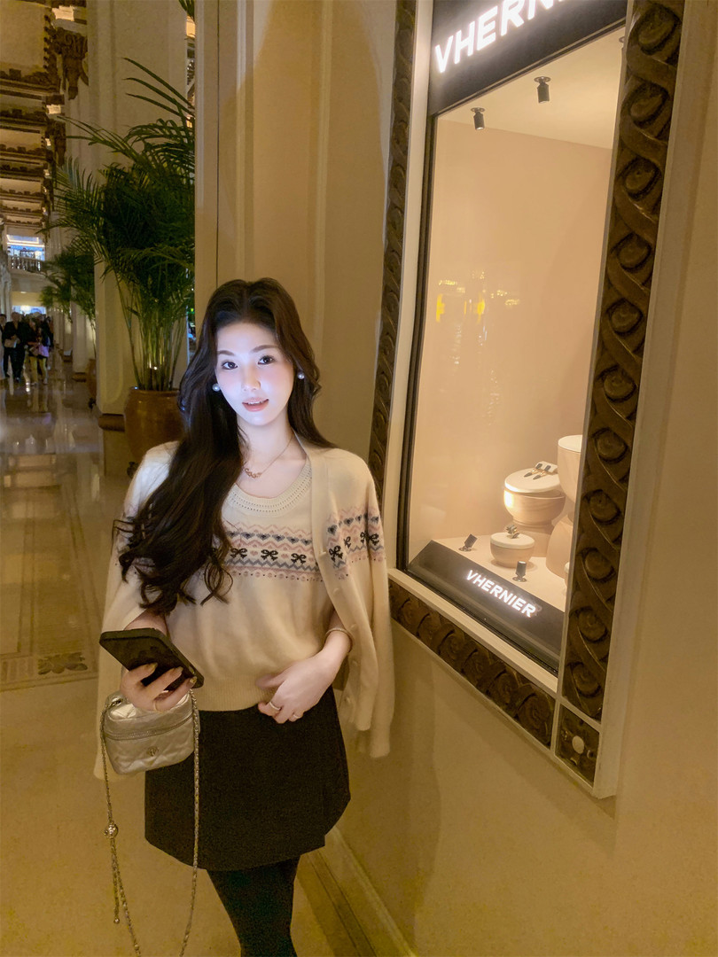 Woman wearing a cream knit sweater and black skirt in a boutique