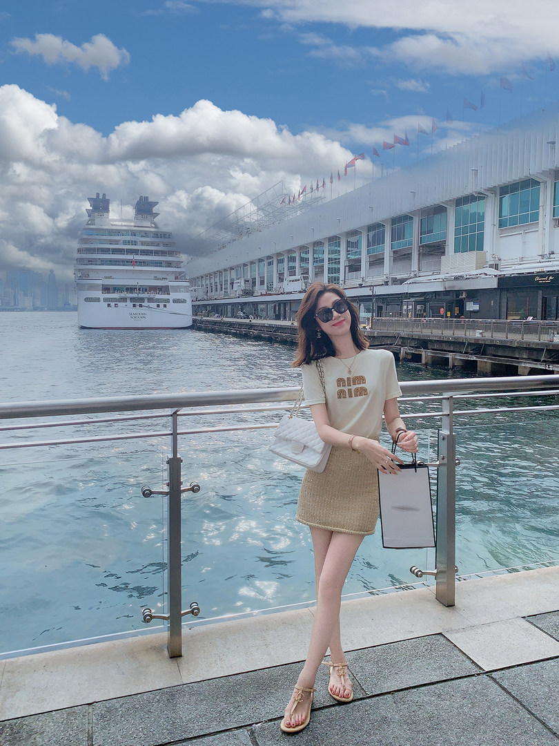 Woman wearing a white top and beige knit mini skirt by the waterfront