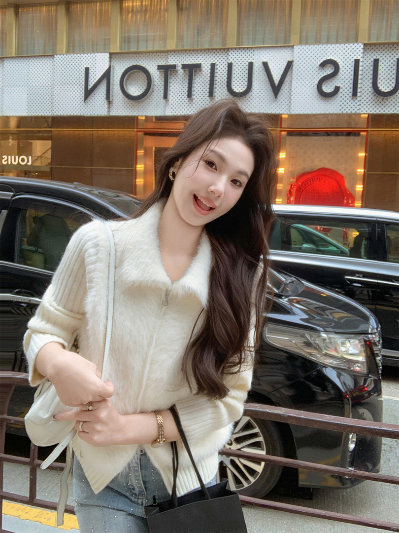 Woman wearing a white fuzzy zip-up cardigan sweater outdoors