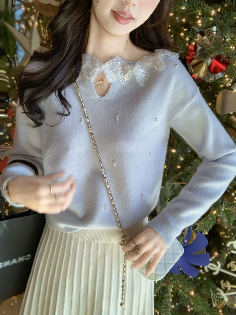 Woman modeling a light blue sheer embellished sweater with a pleated skirt