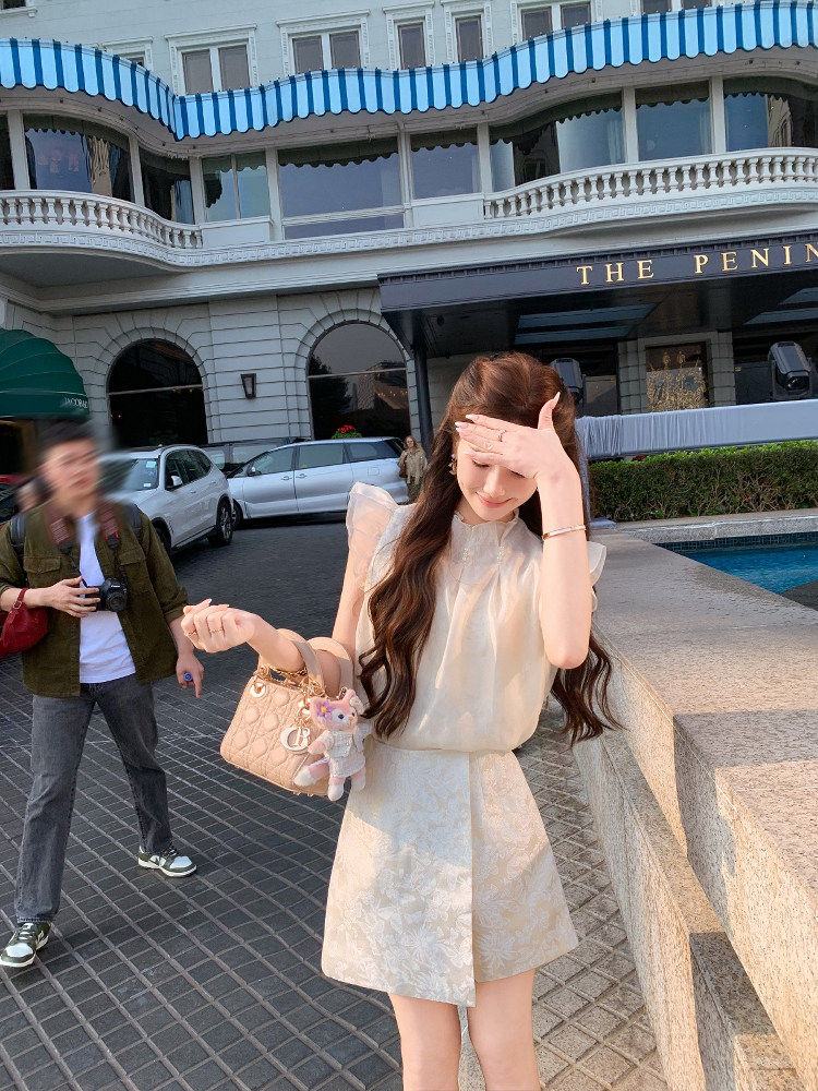 Woman wearing a light cream sleeveless dress outdoors by a hotel