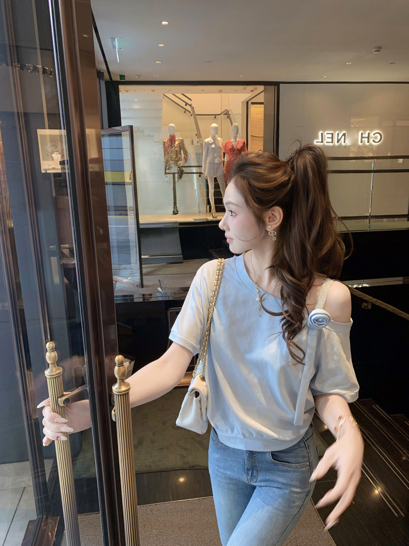 Woman wearing a light blue off-shoulder top with jeans and a small shoulder bag