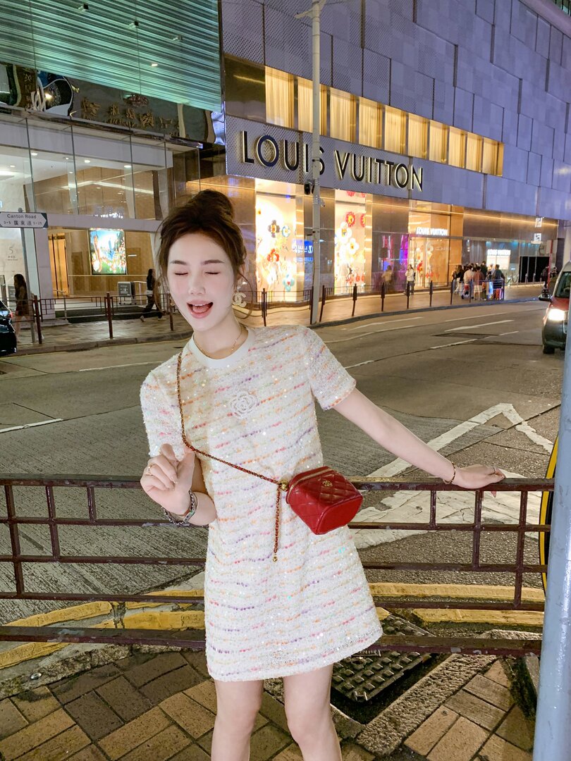 Woman wearing a white sparkly short dress with a red mini bag on the street