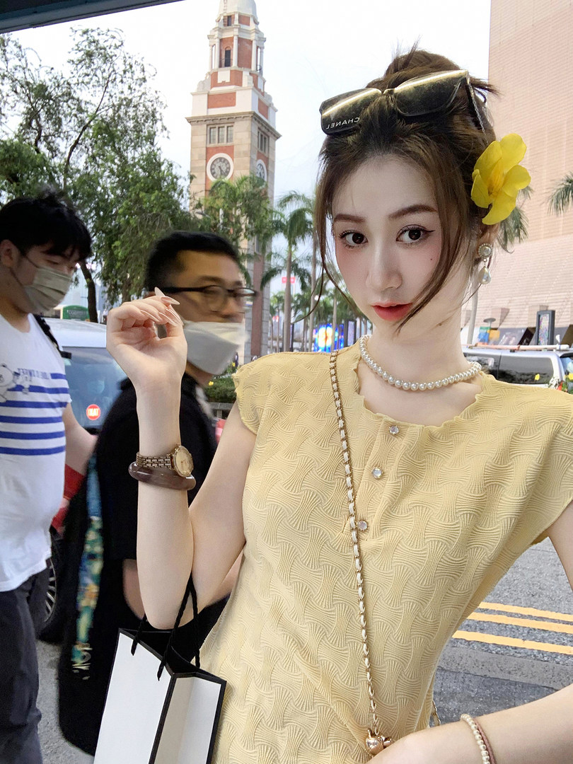 Woman wearing a yellow textured sleeveless top with jewelry outdoors