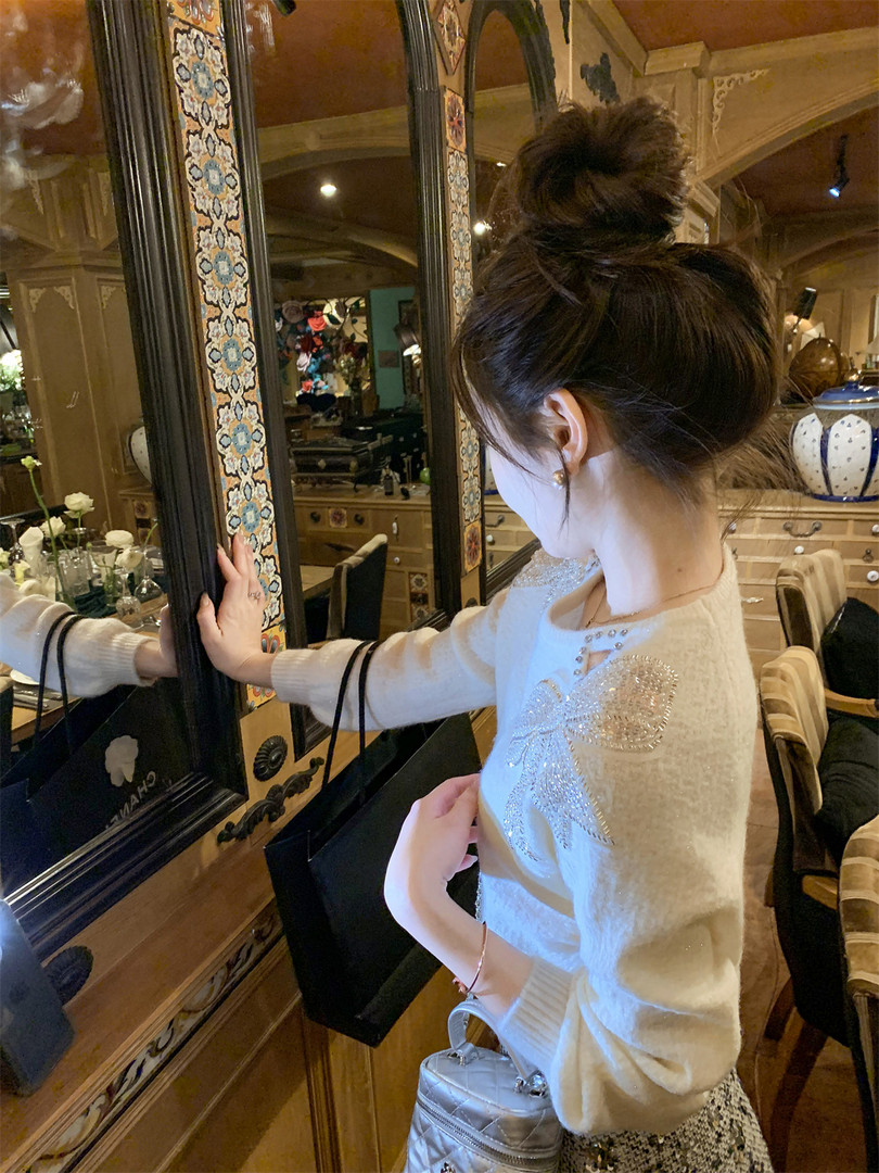 Woman wearing a cream embellished sweater in an indoor setting