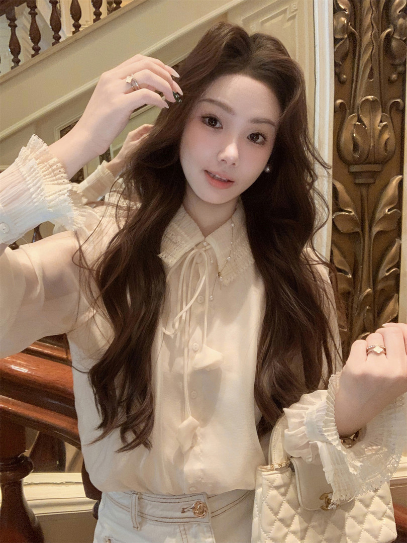 Woman wearing a cream lace-trim blouse with a quilted handbag