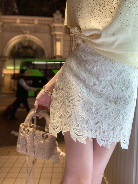 Woman wearing a white lace outfit and holding a quilted handbag