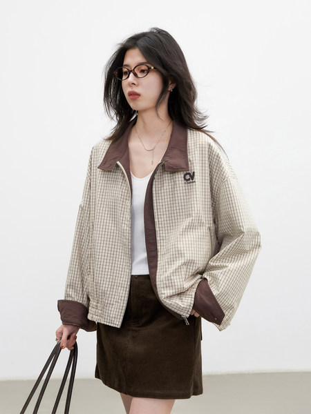 Model wearing a checkered zip-up jacket with brown trim and a dark skirt