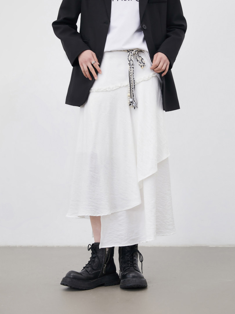Model wearing a black blazer over a white layered skirt with black combat boots