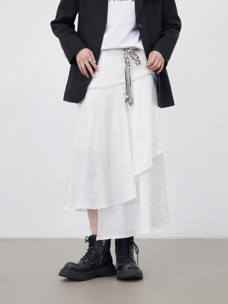 Model wearing a black blazer over a white layered skirt with black combat boots