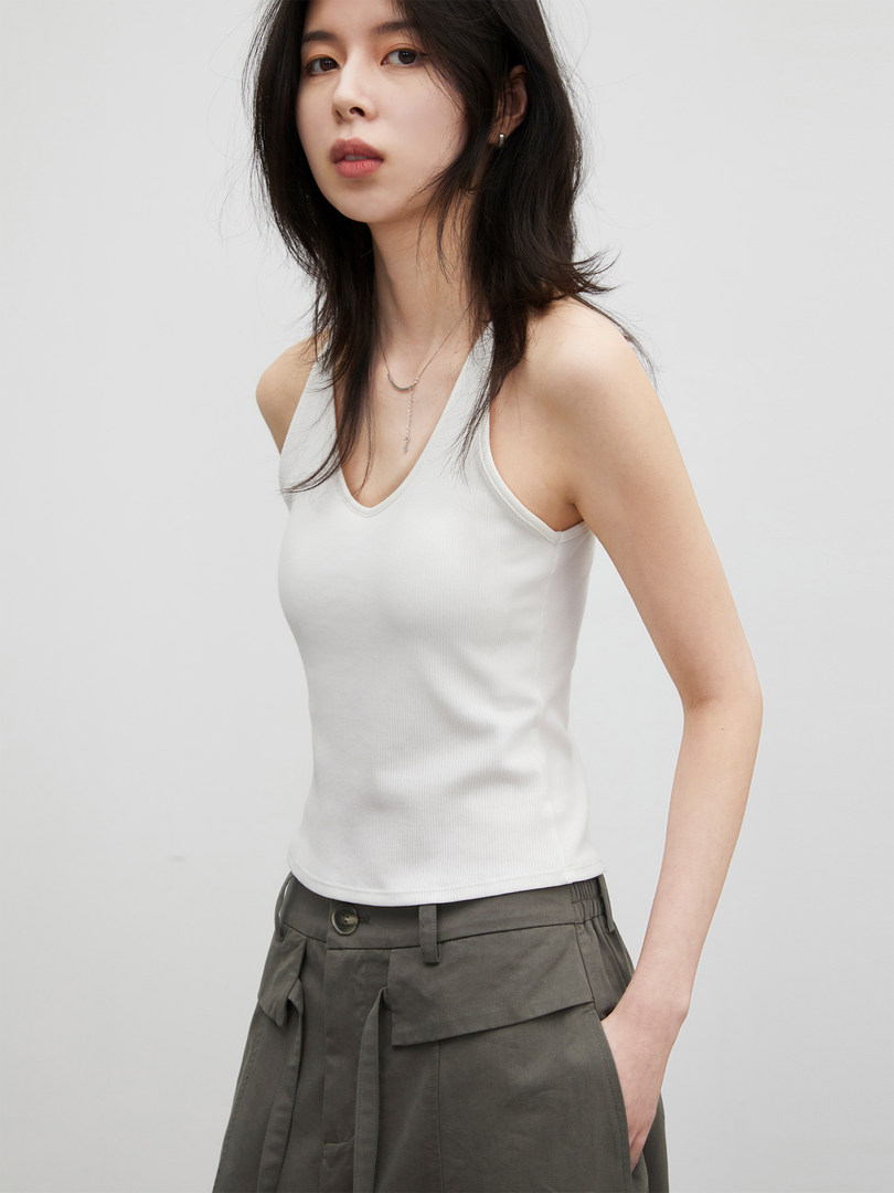 Woman wearing a white sleeveless ribbed tank top with dark trousers