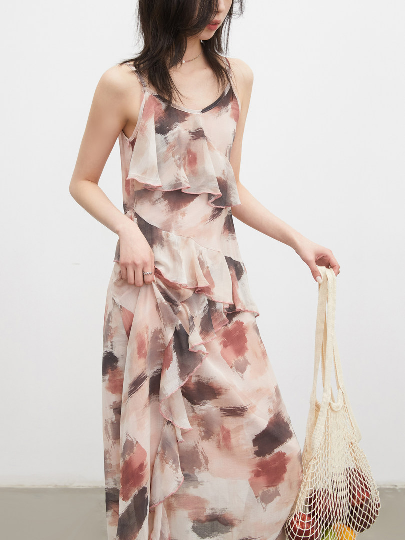 Model wearing a flowy abstract print sleeveless dress with ruffled layers