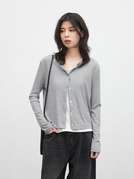 Model wearing a light gray button-front cardigan over a white top and dark pants