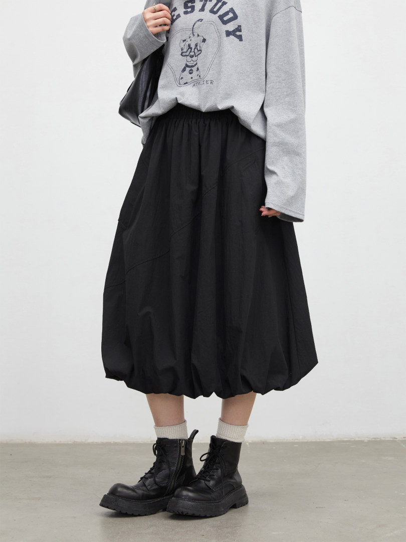 Model wearing a gray graphic sweatshirt with a black midi skirt and black lace-up boots